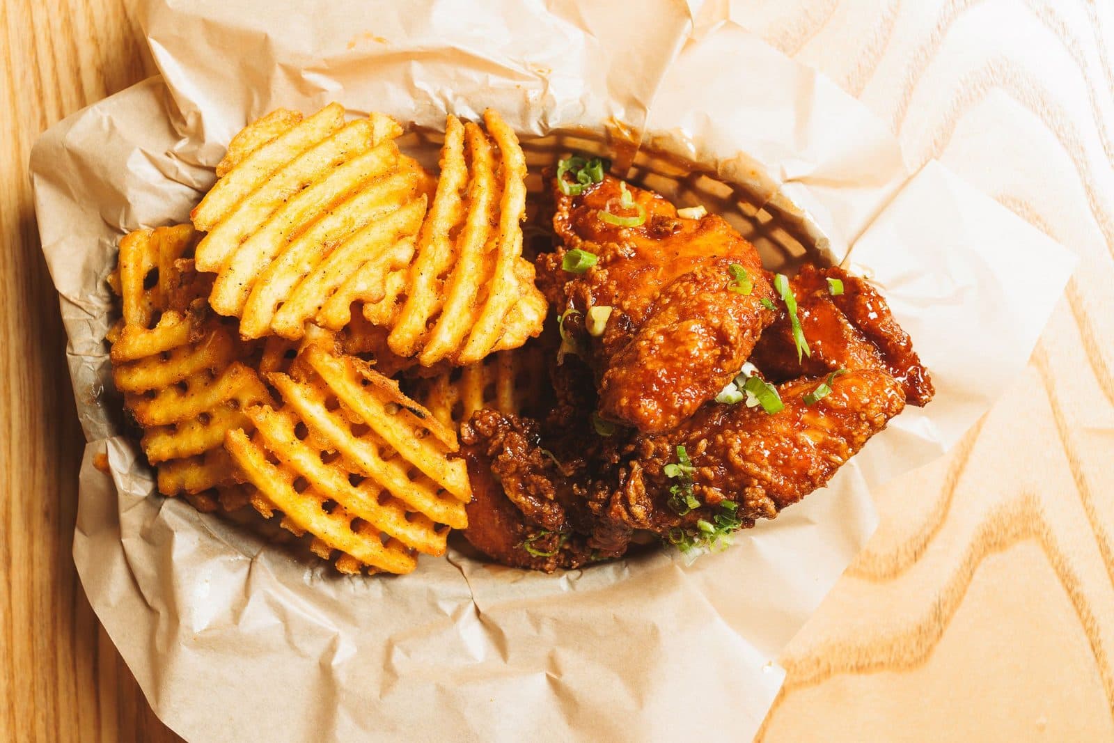 Fried chicken with waffle fries in a paper-lined basket at Chikin Lickin