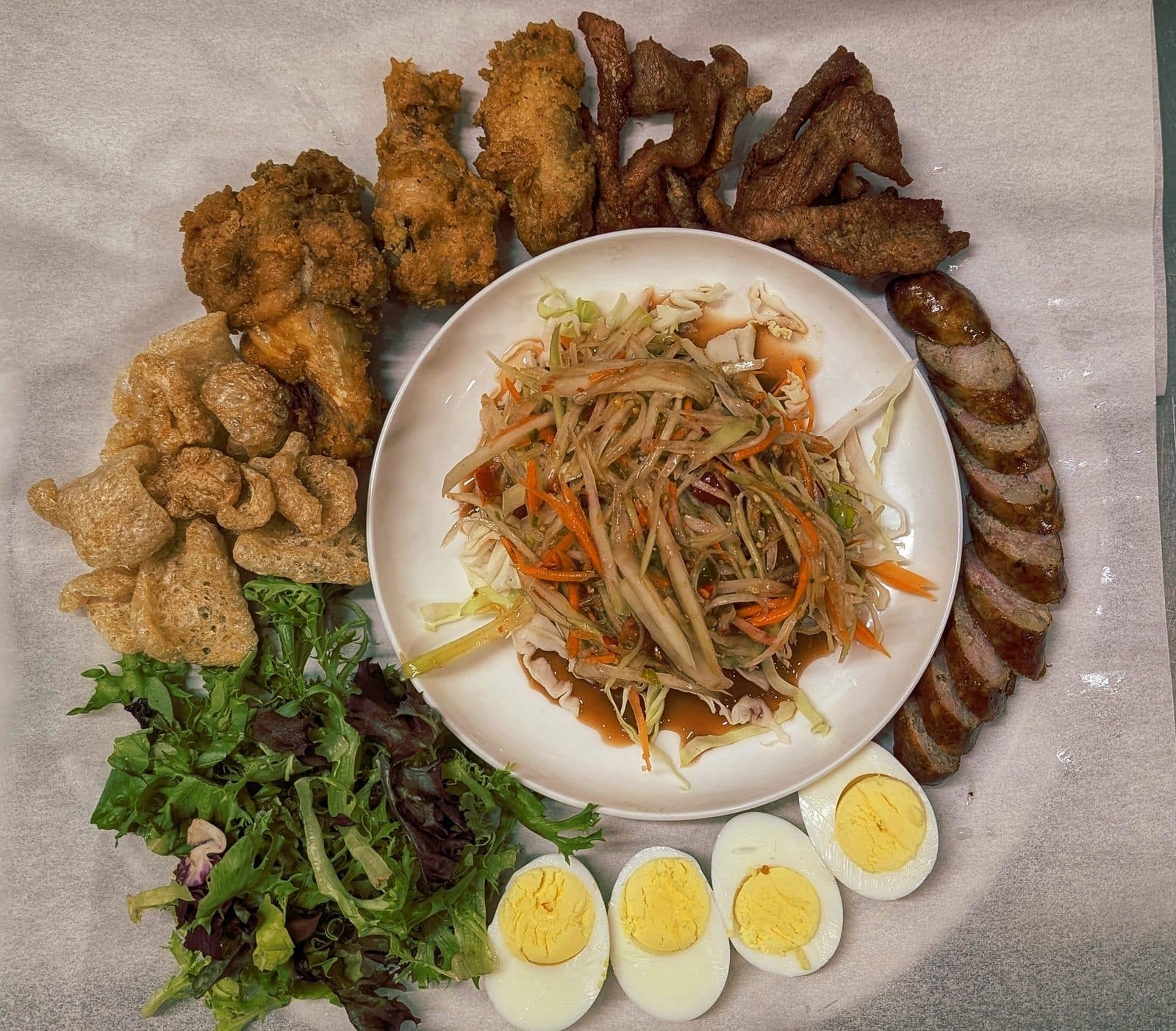 Hoang Khao Combo Special platter with papaya salad, Lao sausage, pork rinds, wings, and eggs