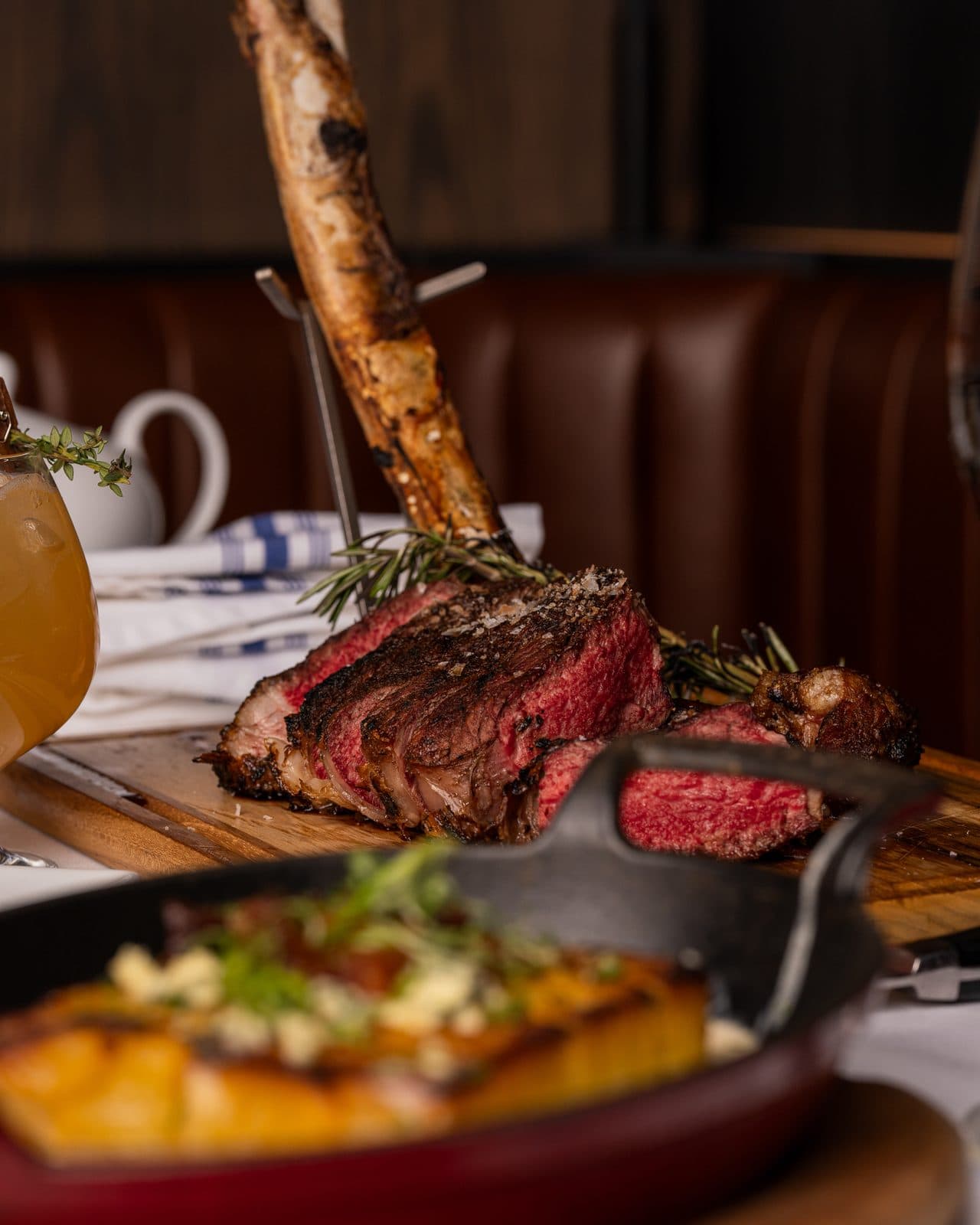 Sliced tomahawk ribeye on a board with a skillet side at Prime and Providence