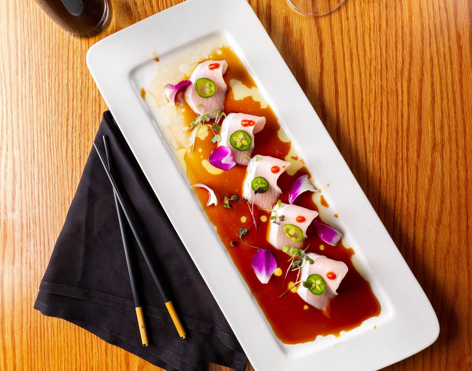 Hamachi chili with jalapeño and ponzu on a long white plate at Wasabi Ankeny
