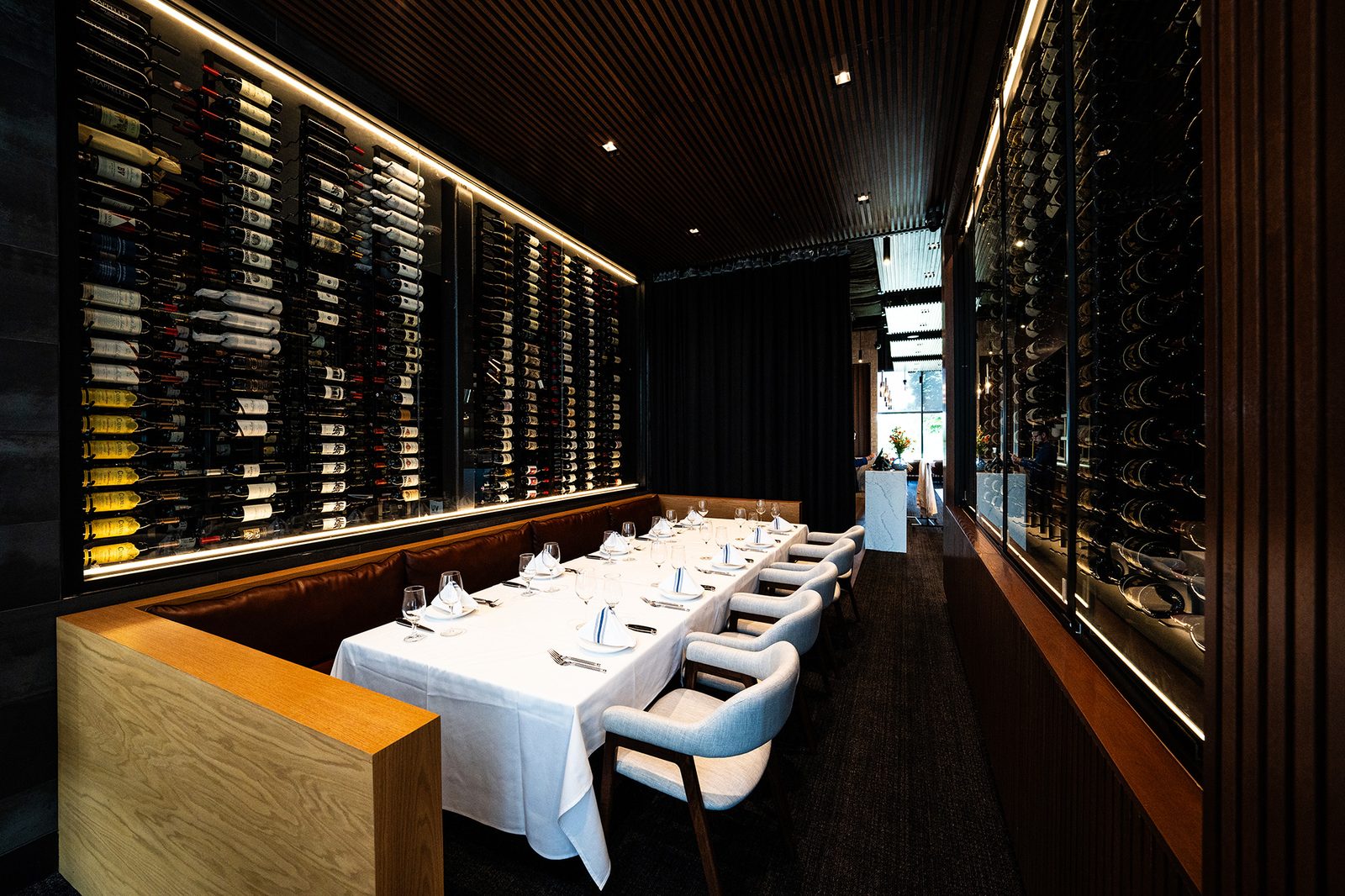 Long dining table set beside a floor-to-ceiling wall of wine at Prime and Providence